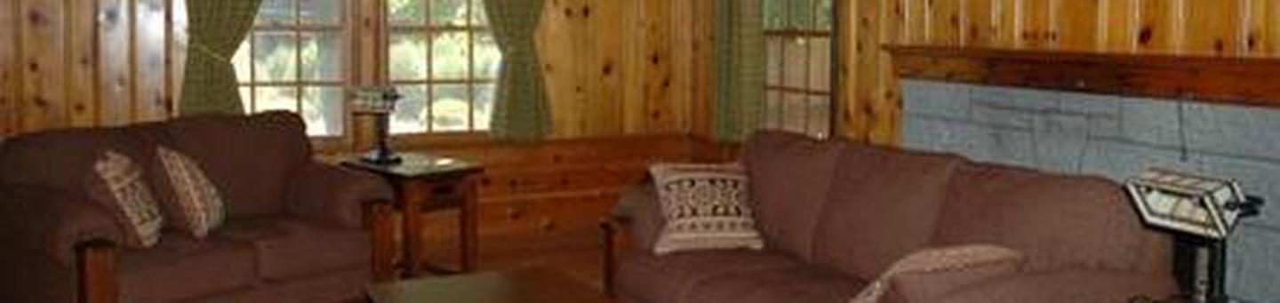 Couch and love seat in wood paneled living room.Ochoco Ranger Rental Living Room