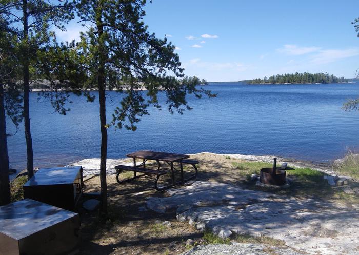 R90 - Anderson Bay West, view looking out from campsite with the bear boxes, picnic table, and fire ring.