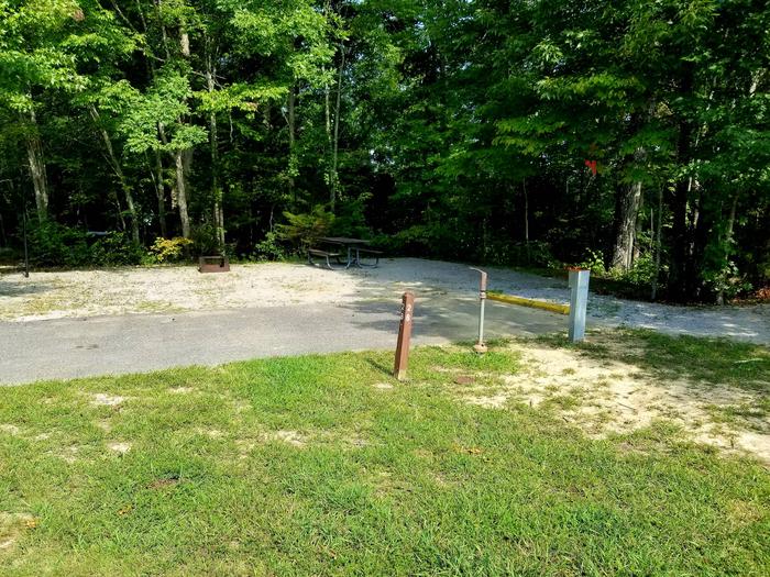 Grassy area in forefront of campsite with paved parking area.Blue Heron Campground Site 26