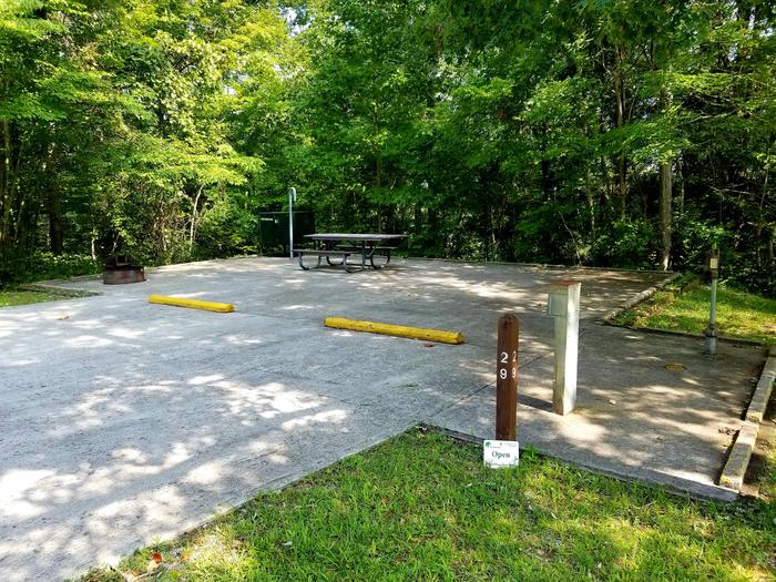 Paved parking area and tent pad with extended picnic table and raised grill.Blue Heron Campground Site 29