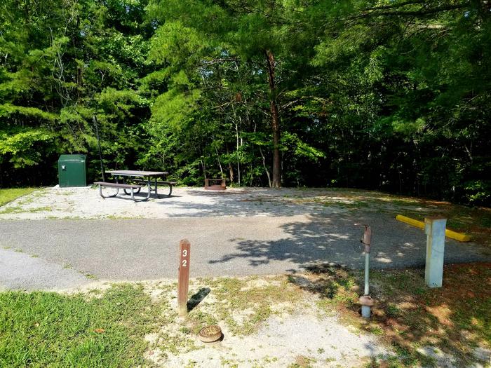 Paved parking area next to gravel tent pad with picnic table.Blue Heron Campground Site 32