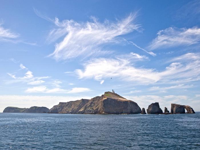 Small island with arch rock and lighthouse on top.Channel Islands National Park