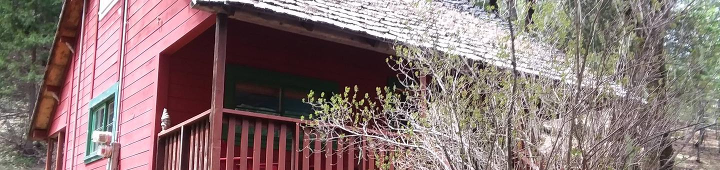 Portion of roof and porch of old, red cabin.Historic Forest Glen Guard Station in the rain.