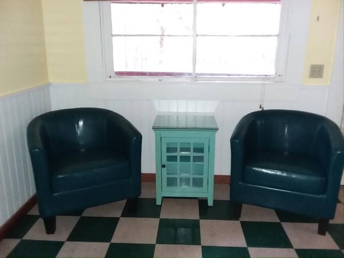 Two blue chairs and small book case.New stylish barrel chairs in the living room of the Forest Glen Guard Station.