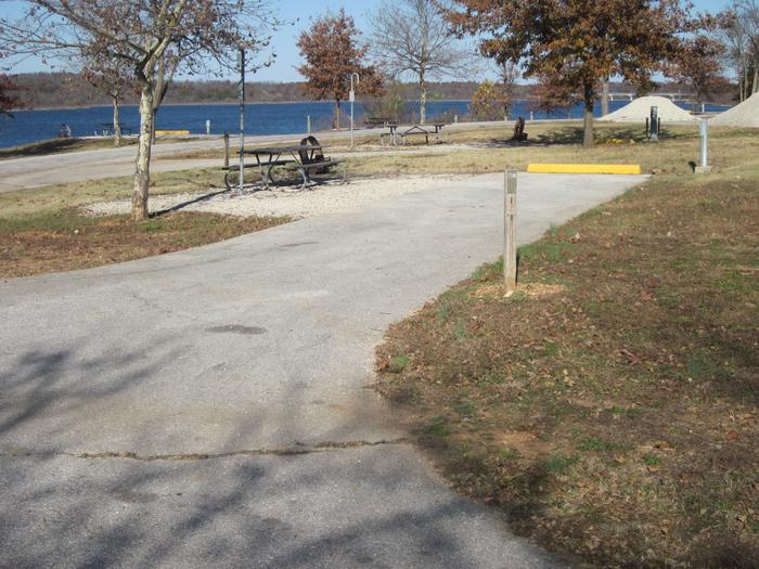 Electric site with paved/gravel pad, picnic table, fire ring, and lantern post.Ruark West site 24