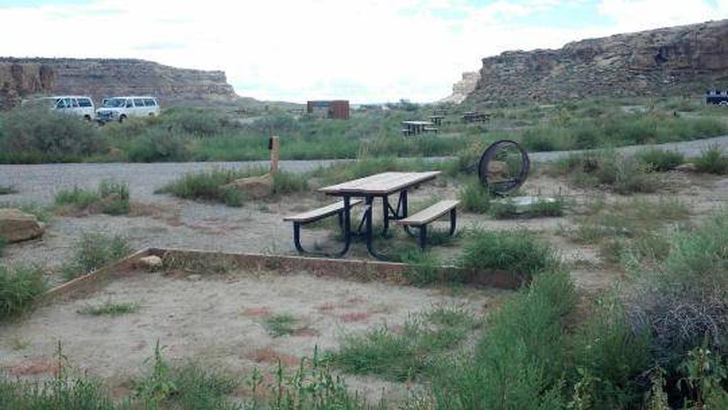 Picnic table, fire grate and tent pad with view of canyon in background