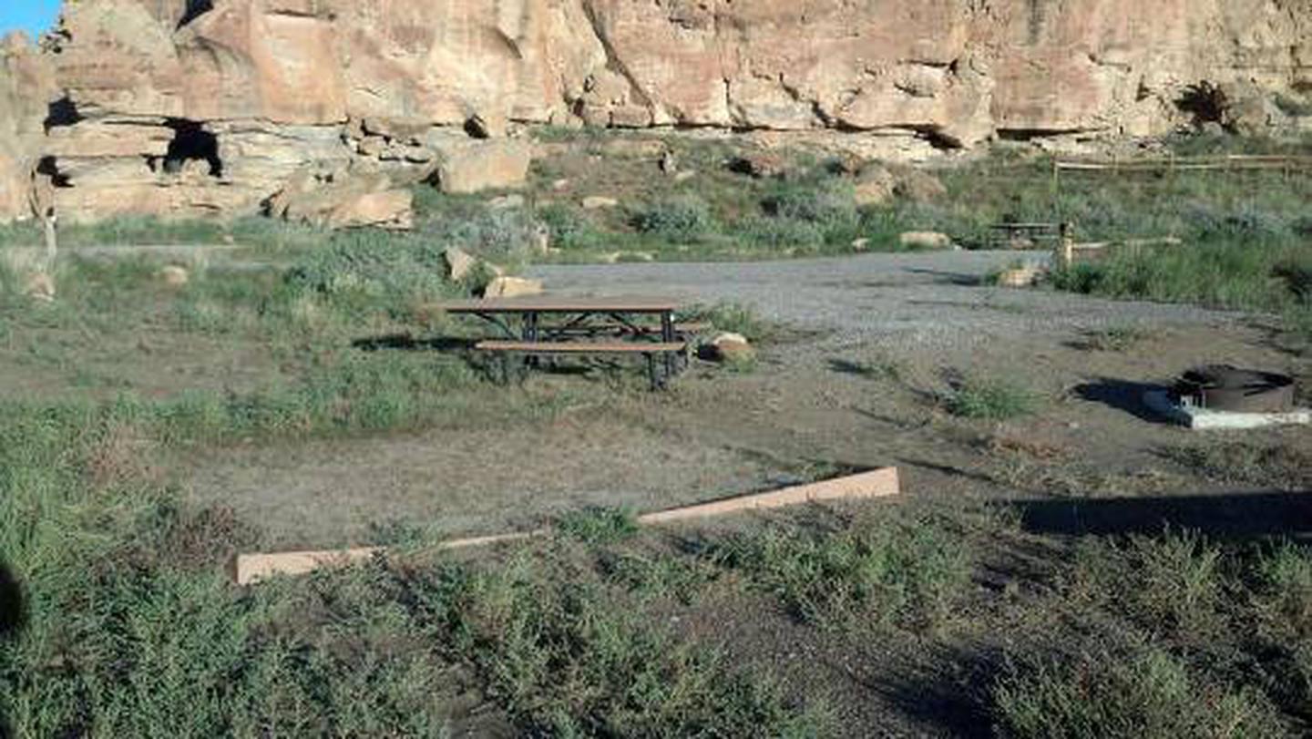 Picnic table, fire grate and tent padPicnic table, fire grate and tent pad in campsite with view of canyon wall in background