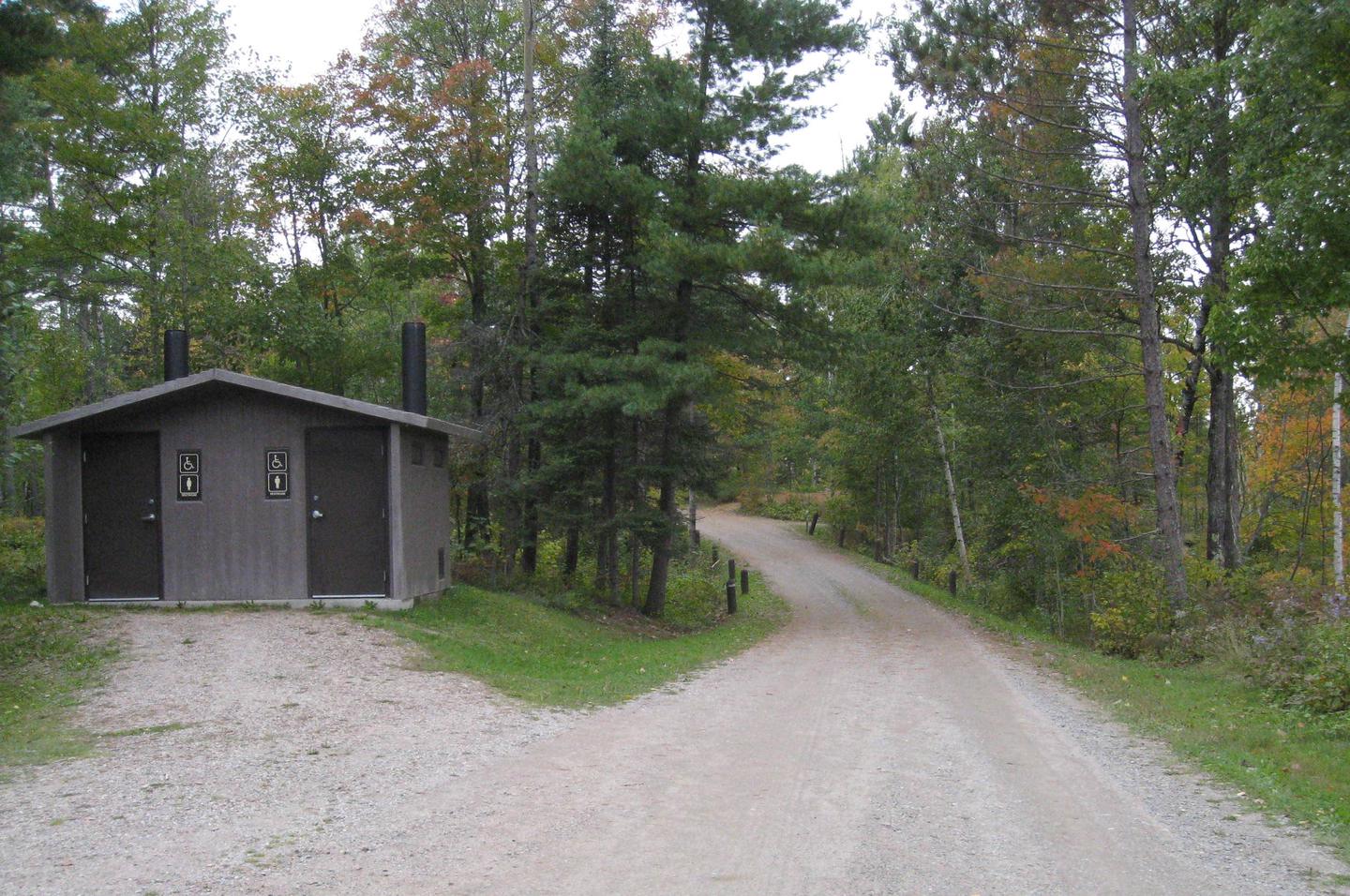 Picture of road and toilet building.View of campground road and bathroom facility, near parking area for hiking trail, beach, and picnic area.