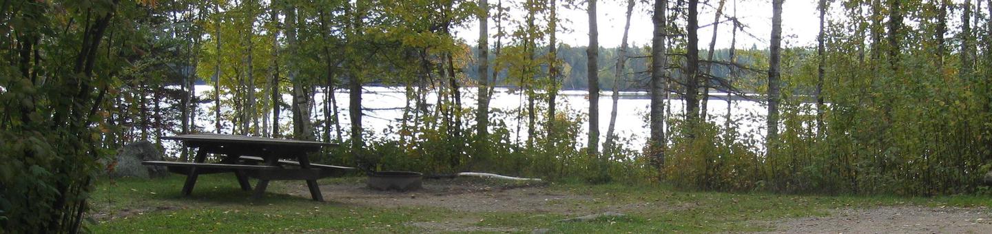 Picture of table with lake in the background.Birch Lake Campsite.
