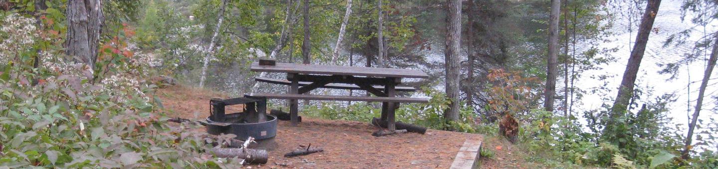 Picture of campsite.Campsite with table, fire ring and tent pad, overlooking Fenske Lake.