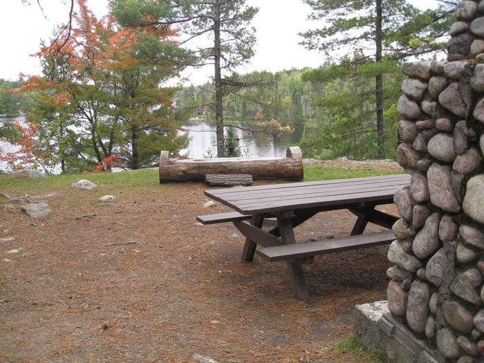 Picture of campsite.Log bench located in the picnic area of the group site.