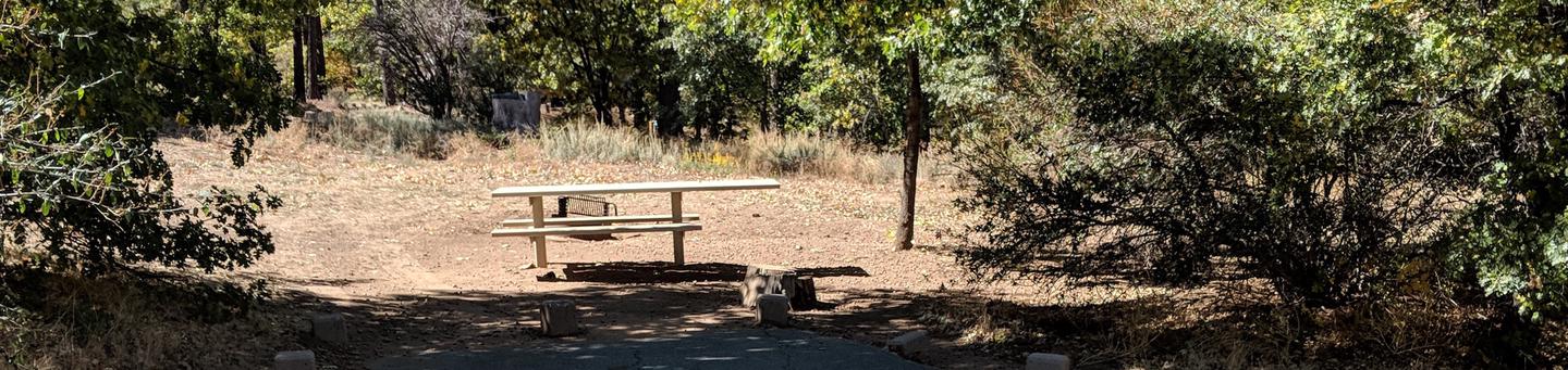 Burnt Rancheria Campground Site #6 featuring entrance to the wooded site and picnic table.