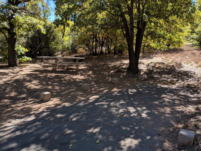 Burnt Rancheria Campground Site #9 featuring entrance to the wooded site and picnic table.