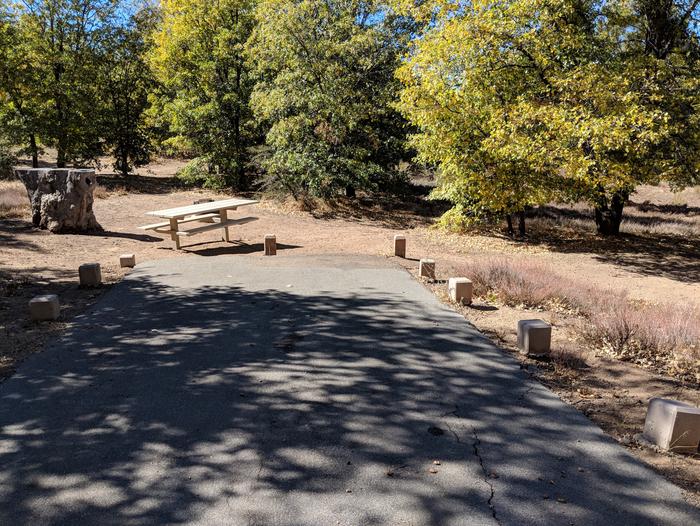 Burnt Rancheria Campground Site #50 featuring entrance to the wooded site and picnic table.
