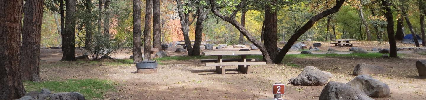 Manzanita Campground site #02 featuring the treed picnic area, camping space, and fire pit.