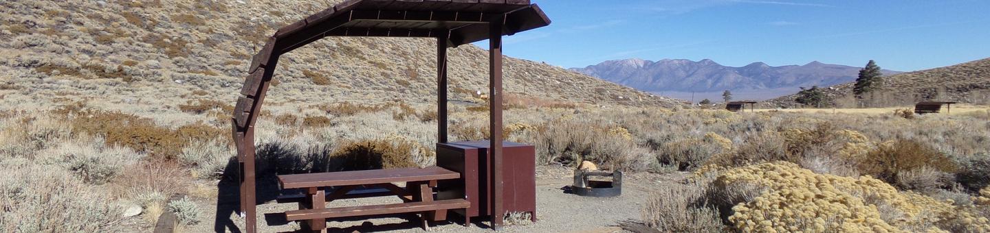 McGee Creek Campground site #12 featuring shaded picnic area with fire pit and camping space. 