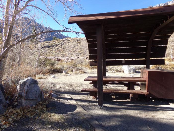 McGee Creek Campground site #26 featuring shaded picnic area with fire pit and camping space. 