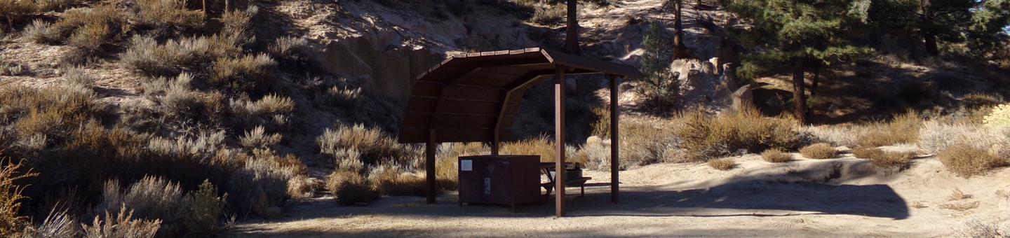 Tuff Campground site #14 featuring shaded picnic area with camping space and fire pit by the mountain side. 