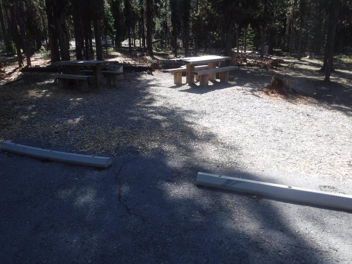Flat campsite with two picnic tables and a fire ring. J-07