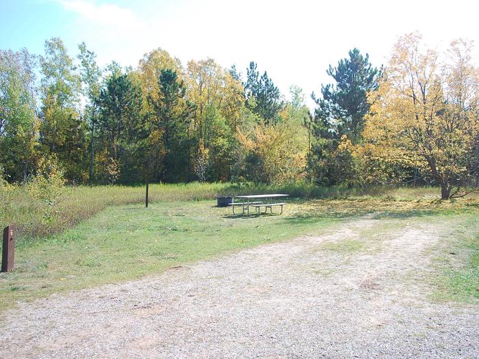 Bay Furnace Campground site #06; heavily treed site with picnic table and fire pit. 