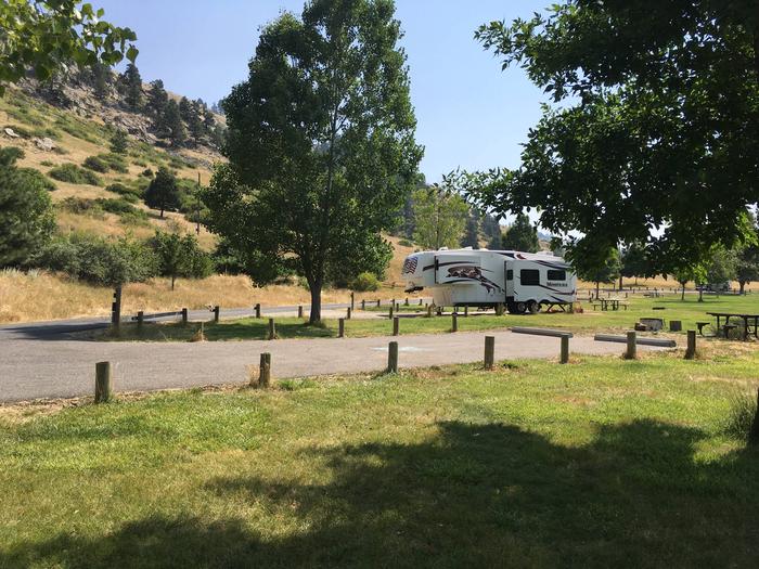 Side view of ADA site that is paved at Holter Lake Campground. Site 26 has paved access to the site. Picnic table and fire pit are at the far end of the campsite.Site 26 BLM Holter Lake Campground
