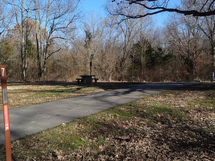 This site is furnished with a fire pit and picnic table on the left side of a paved pad. Hookups are on the right rear side of the pad. 