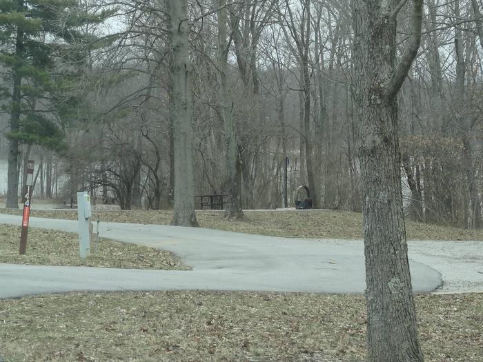 Pull through type site with picnic table and fire pit on the right of camp pad, and water and electric on left of camp pad