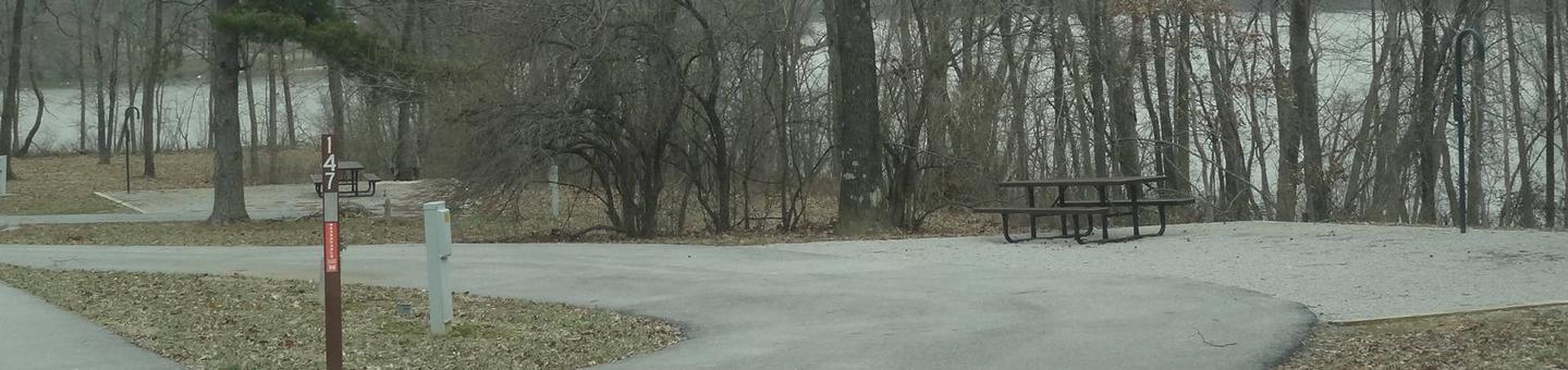 Pull through type site with picnic table and fire pit on the right of camp pad, and water and electric on left of camp pad