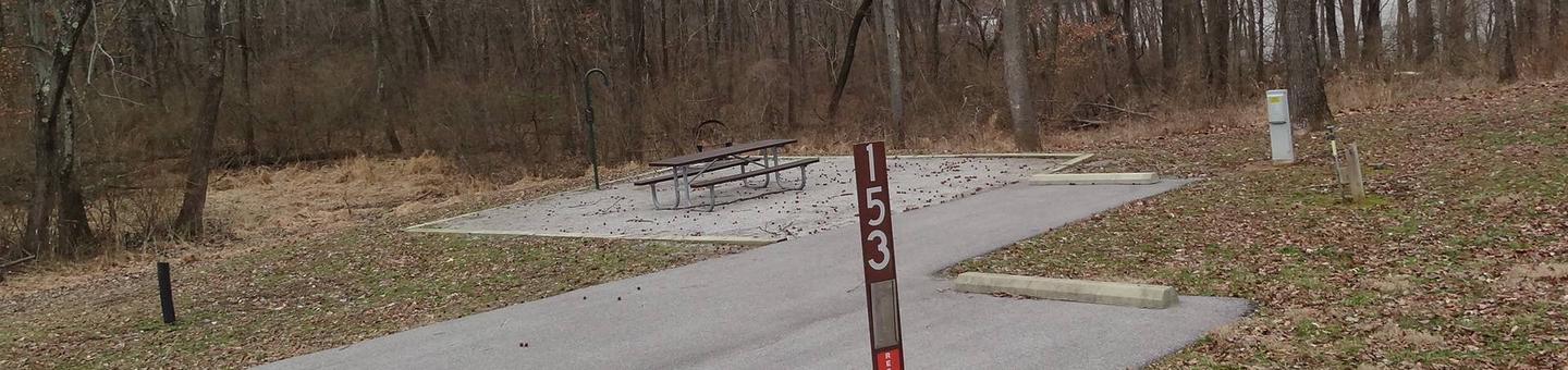 picnic table and fire pit to the left of camp pad, electric, water, and extra parking to the right of pad.