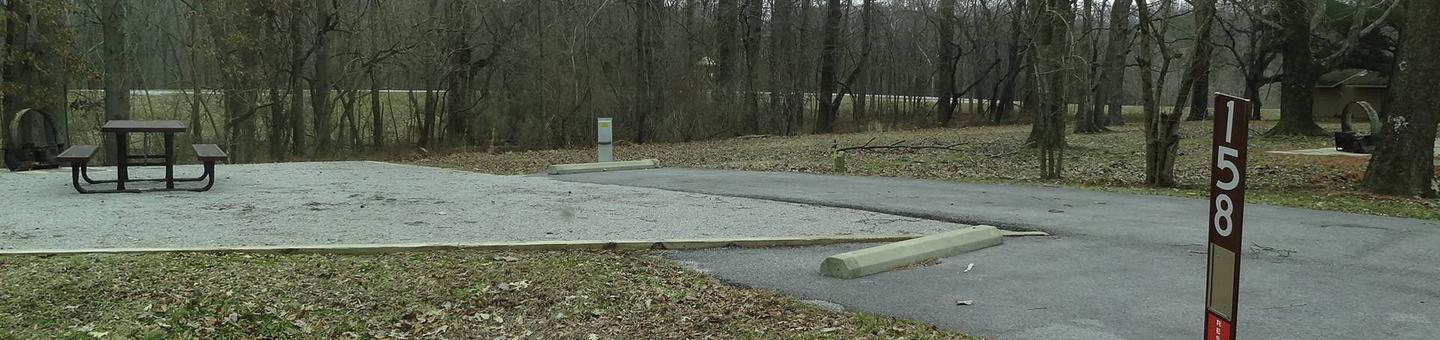 picnic table, fire pit, and extra parking to the left of camp pad, electric and water to the right of pad.