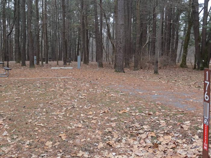 picnic table and fire pit to the left of camp pad, electric, water, and sewer to the right of pad.