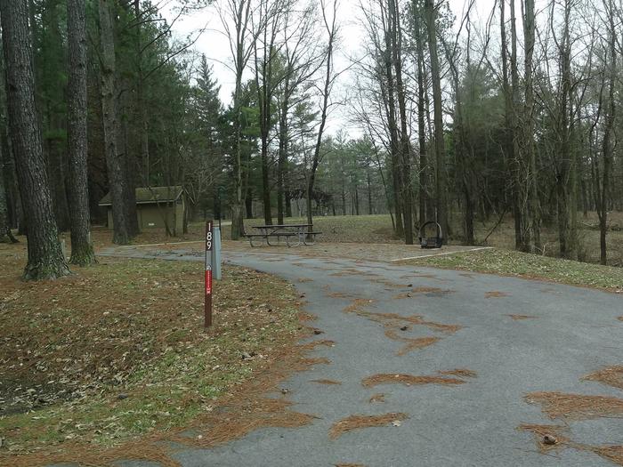 picnic table and fire pit to the right of camp pad, electric, water, and sewer to the left of pad.