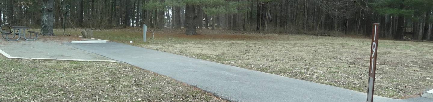 picnic table and fire pit to the left of camp pad, electric, water, sewer, and extra parking to the right of pad.