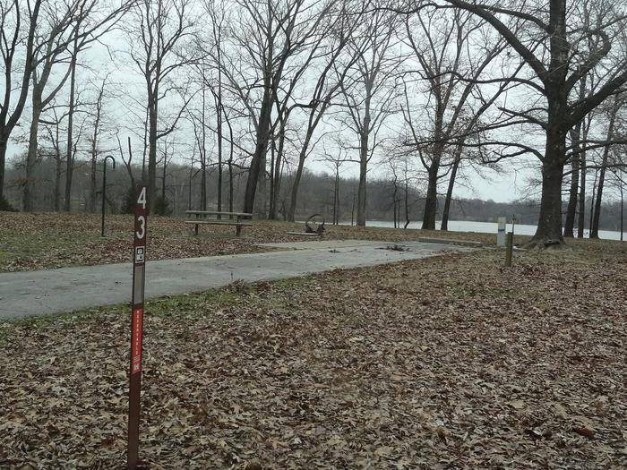 picnic table and fire pit to the left of camp pad, electric, water, and sewer to the right of pad.