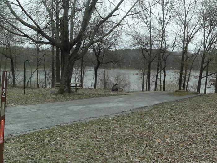 picnic table and fire pit to the left of camp pad, electric to the right of pad.