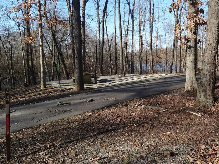  This site has many trees surrounding it, providing lots of shade. The fire pit and picnic table (sitting on a concrete pad) are located on the left side of the paved pad. Hookups are on the right side. The rear of this site is near the lake giving you a great view. 