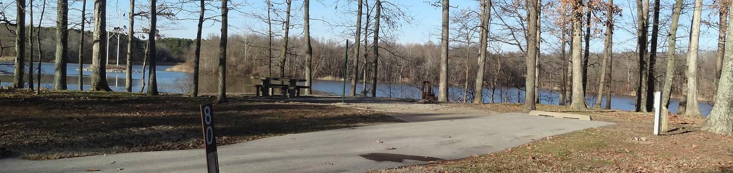 This site has a great view of the lake. The picnic table and fire pit are located on the left side of the paved parking/camping pad. The hookups are on the right side of the pad. 