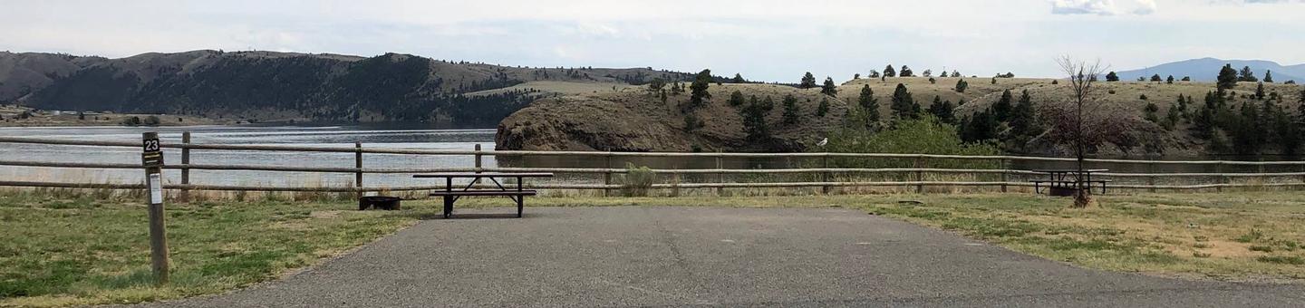 Site 23 at BLM White Sandy Campground. Paved access within campground. Paved camping pad with fire pit and picnic table. No shade at this location. Lakeside campsite on Hauser Lake. Wooden fence in the background to protect bank stabilization.Site 23 BLM White Sandy Campground.