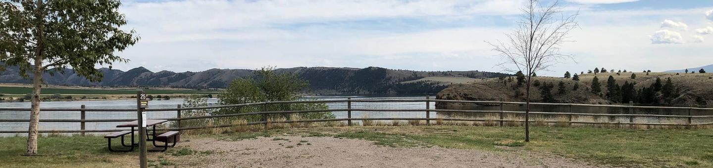 Site 25 at BLM White Sandy Campground. Paved access within campground. Gravel camping pad with fire pit and picnic table. Wooden fence in the background to protect bank stabilization. Lakeside campsite on Hauser Lake.Site 25 BLM White Sandy Campground.