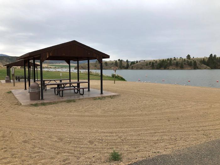 BLM White Sandy Campground beach area on Hauser Lake with paved parking for day-users. Sandy beach with 2 shade structures and picnic tables.BLM Butte Field Office White Sandy Campground.