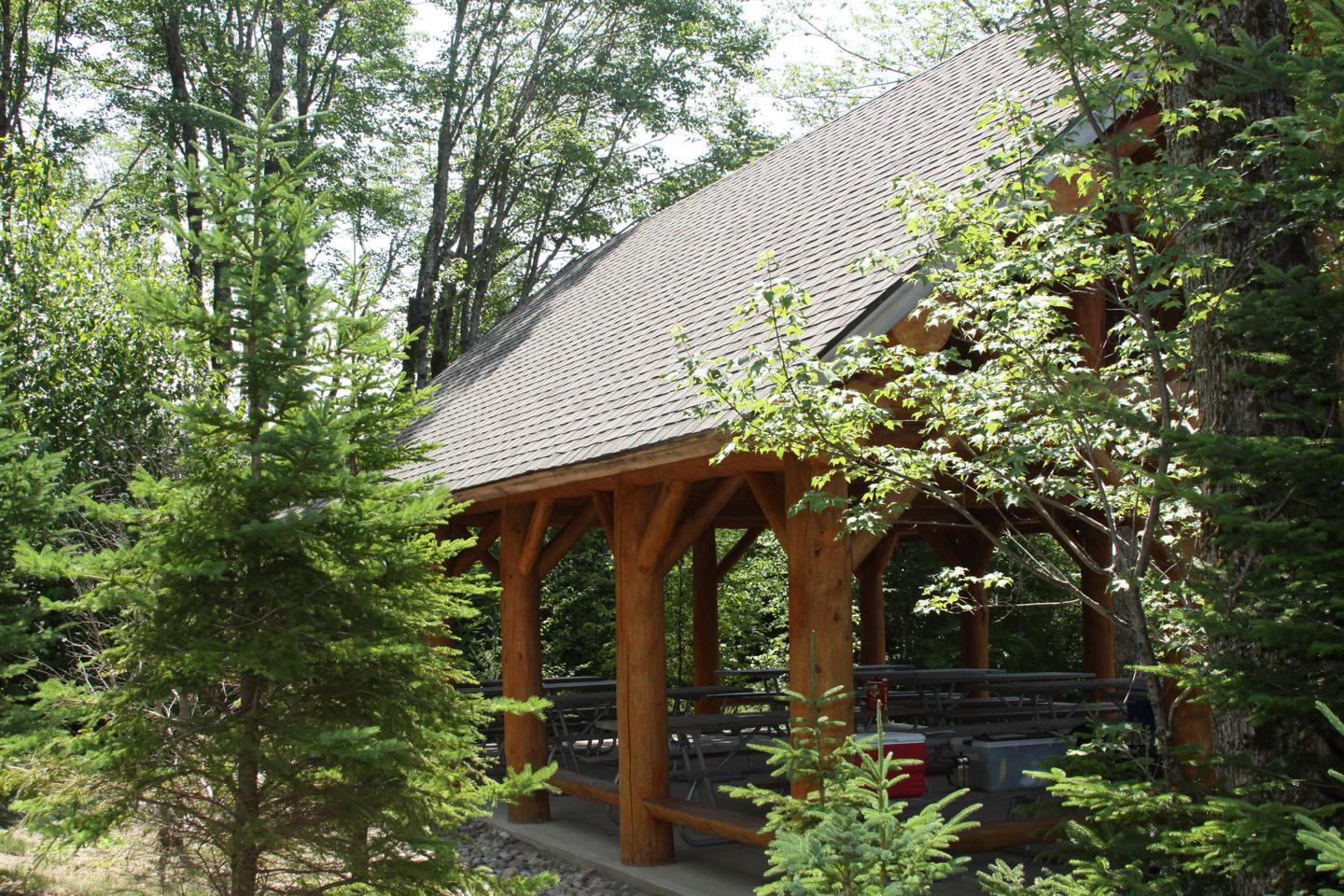 Exterior view of log cabin style picnic pavilion surrounded by spruce and pine trees.Pavilion for group campsites (Photo 1 of 2)