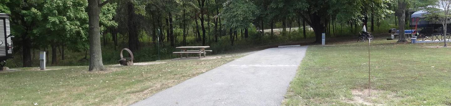 This site has a picnic table and fire pit located to the left side of the paved parking/camping pad. The electrical hookup is on the right. 