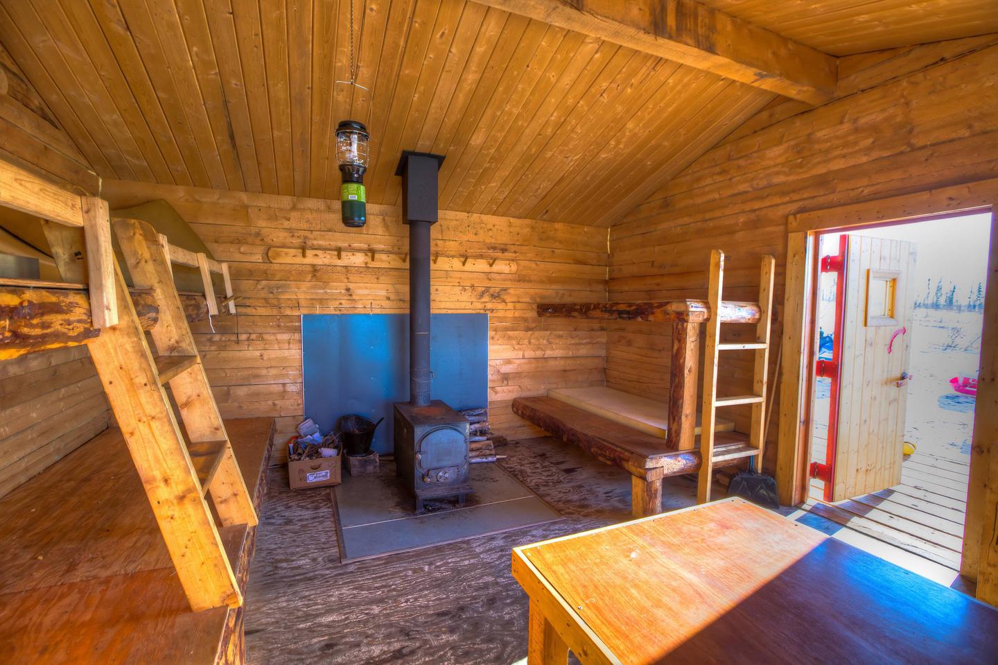 Bunks and woodstove in a log cabinBunks, table, and woodstove in Crowberry Cabin.