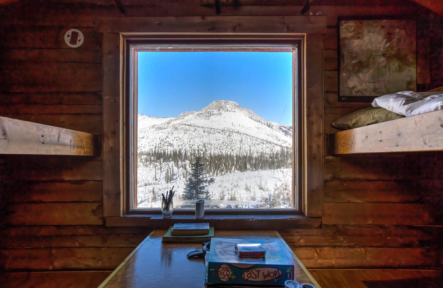 View of mountain through a log cabin windowWindow view from Caribou Bluff Cabin