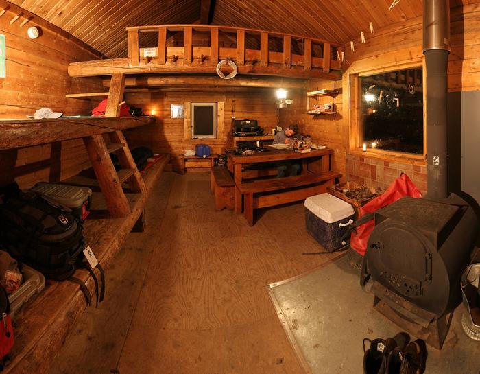 Log cabin interior with bunks, table, and woodstoveInterior of Lee's Cabin
