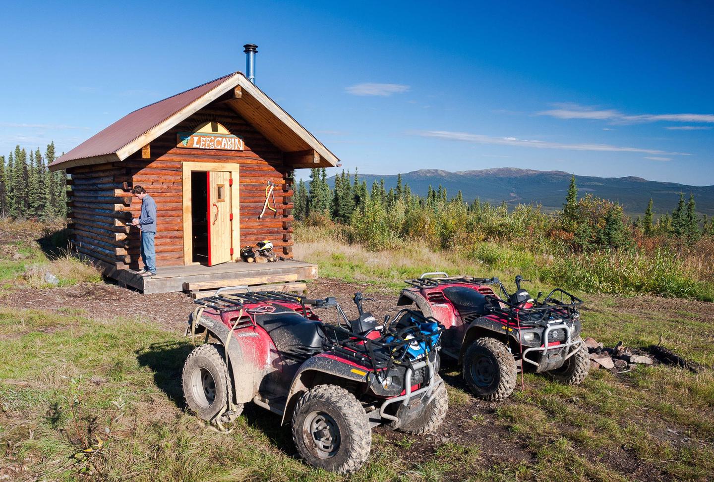 Two all-terrain vehicles parked in front of a log cabinLee's Cabin, unlike many of the White Mountains cabins, is readily accessible in summer.
