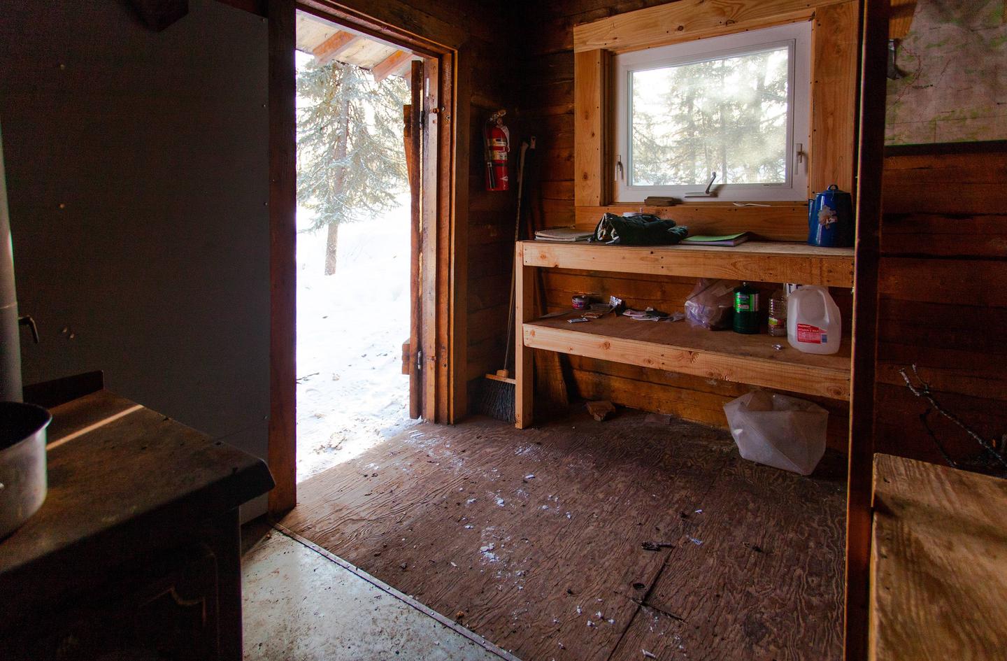 Interior of log cabin looking out the doorCooking counter at Wickersham Creek Trail Shelter