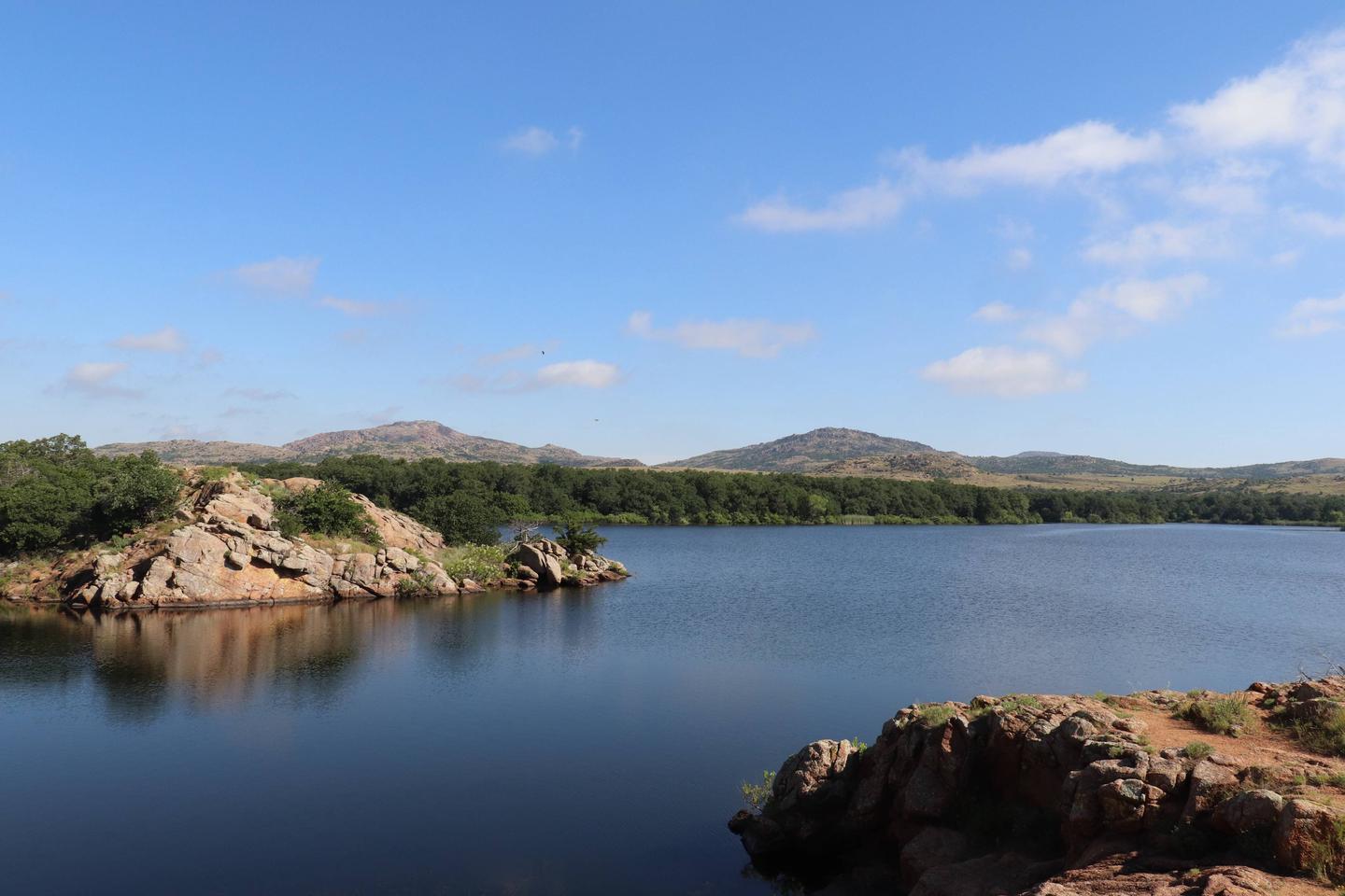 The Wichita Mountains line the horizon beyond the pink granite shore of Quanah Parker Lake.The Wichita Mountains line the horizon beyond the shore of Quanah Parker Lake.