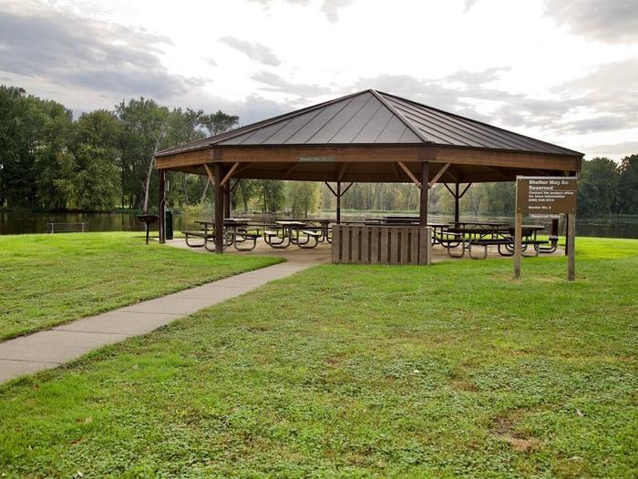 Shelter 3Round picnic shelter with water behind the shelter.  Large parking lot with playground between shelter and beach.