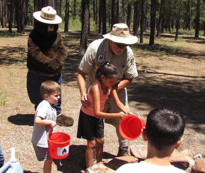 Smokey Bear oversees as children learn how to extinguish a campfireForest Naturalists offer interpretive and interactive programs every weekend in the Rim Lakes Recreation Area campgrounds
